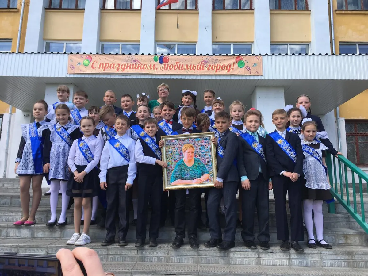 Выпускники вручают учительнице фотомозаику у школы